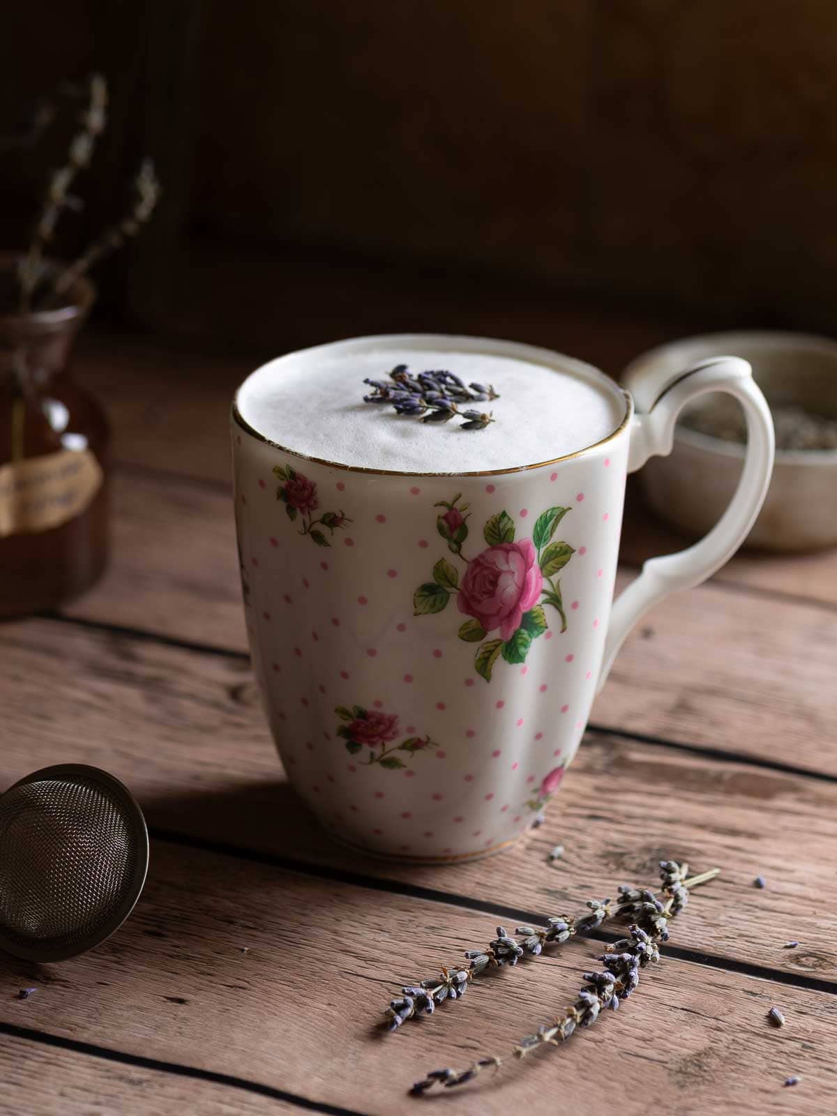 Lavender tea latte in a floral mug on top of a wood surface.