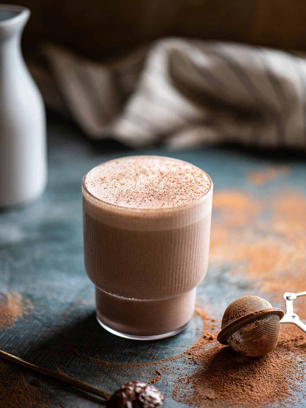 Smoothie in a clear glass with cocoa powder on top.