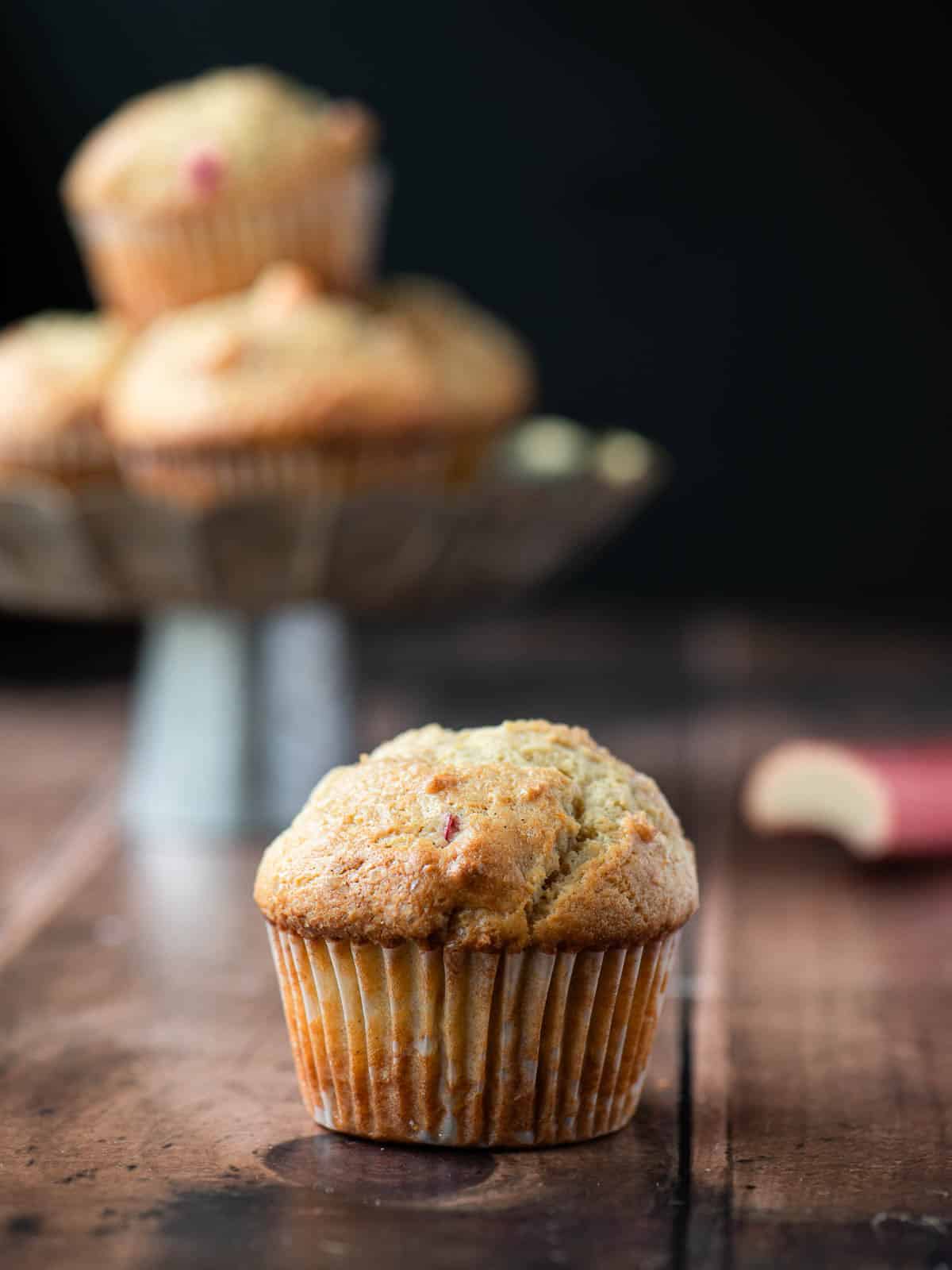 Close up of a rhubarb muffin with a stack of muffins behind it.