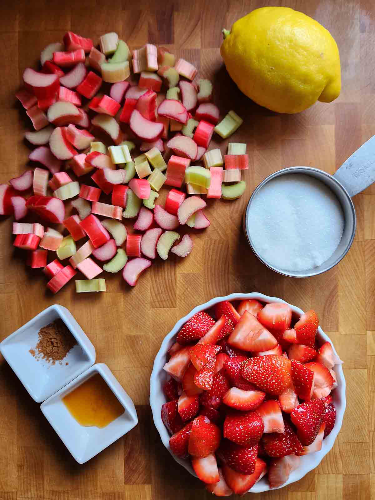 Overhead of ingredients for fruit jam on a wood cutting board.
