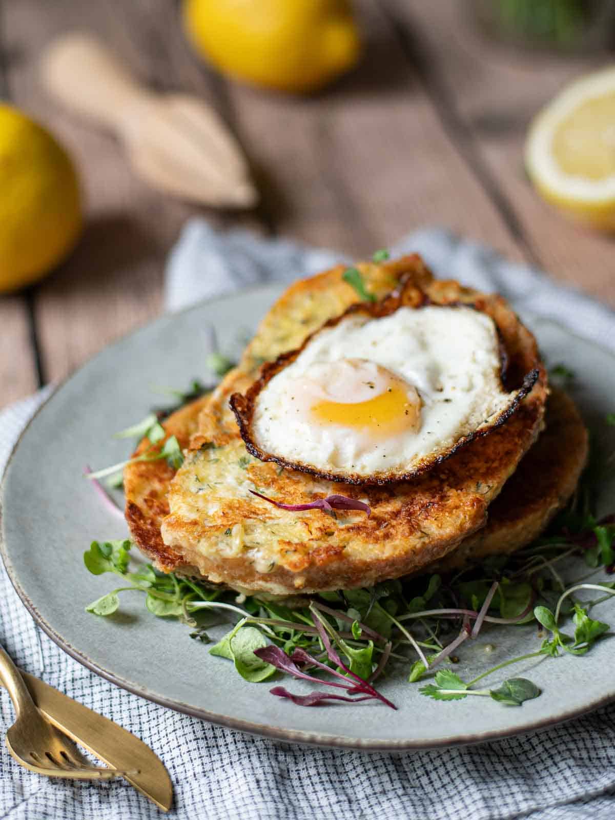 Angled view of savory French toast with a fried egg on top over greens.