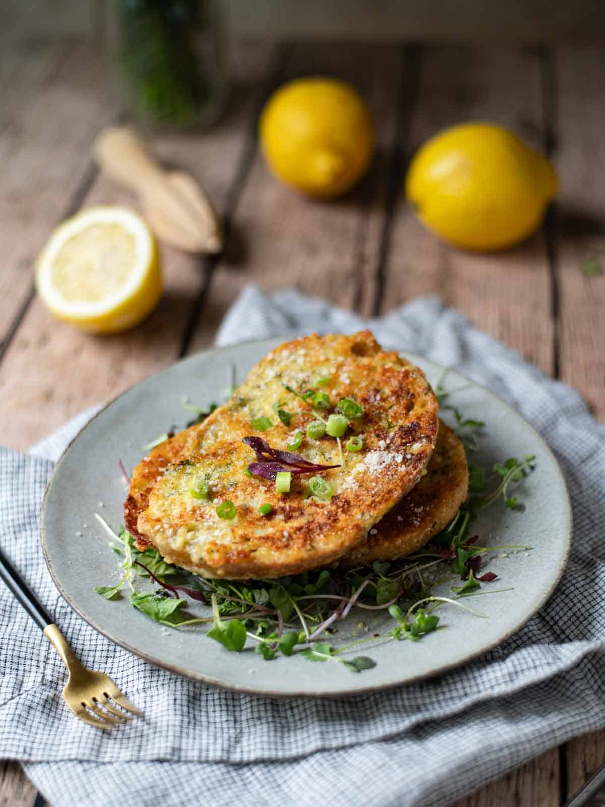 A plate of French toast over microgreens on a wooden table with lemons.