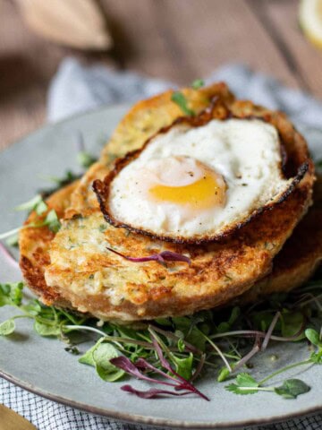 Angled view of savory French toast with a fried egg on top over greens.