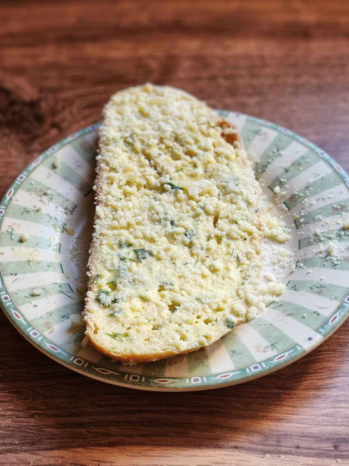 Bread dipped in parmesan cheese on a green plate.