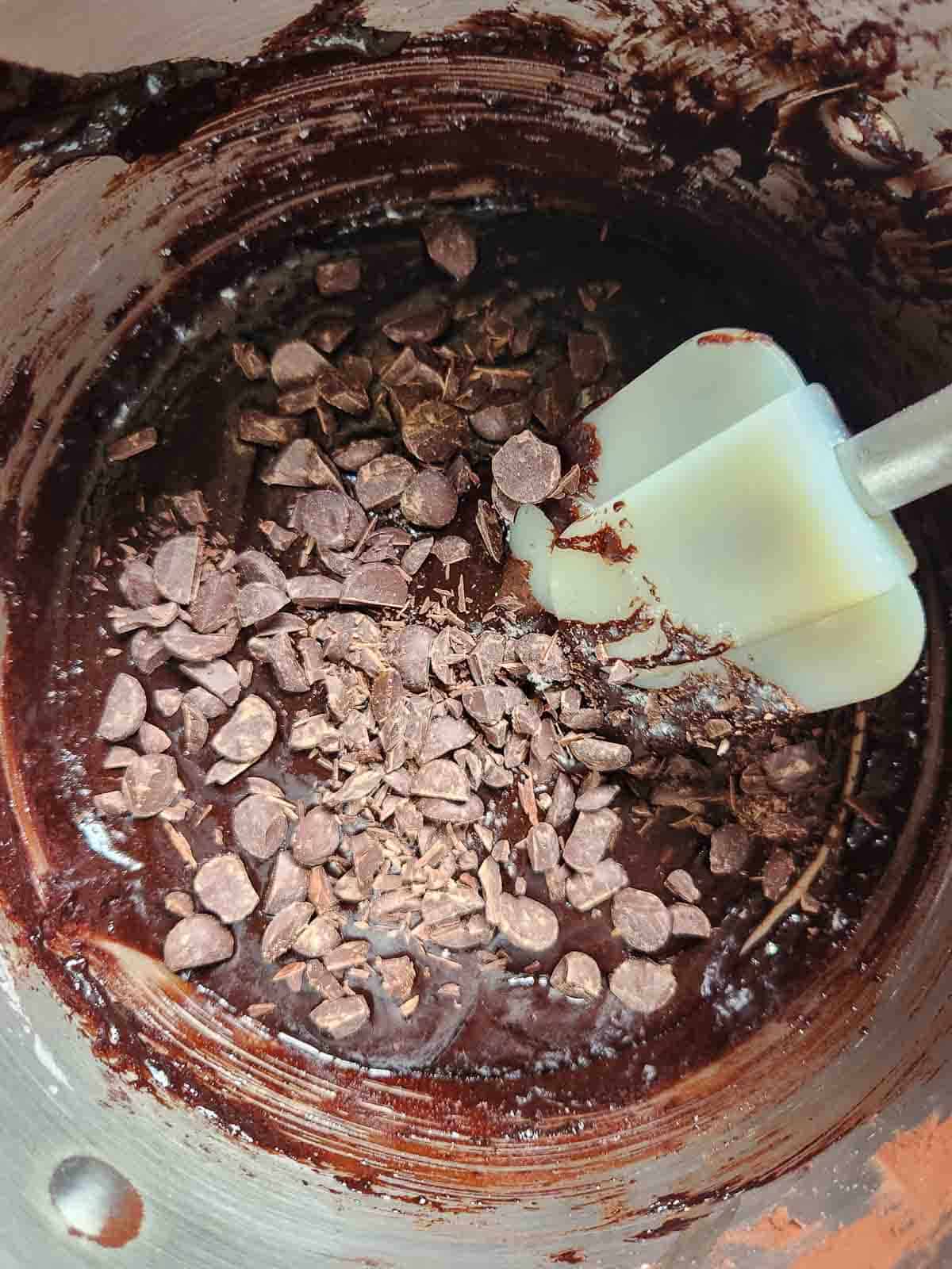 Folding chocolate chips into brownie batter with a spatula.