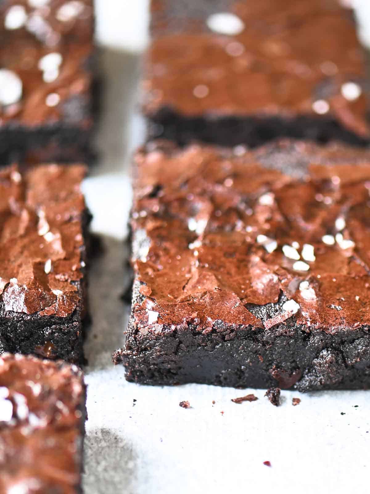 An angled view of Valrhona chocolate brownies on parchment paper.