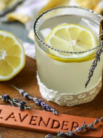 Lavender lemonade in a glass with a wooden sign.
