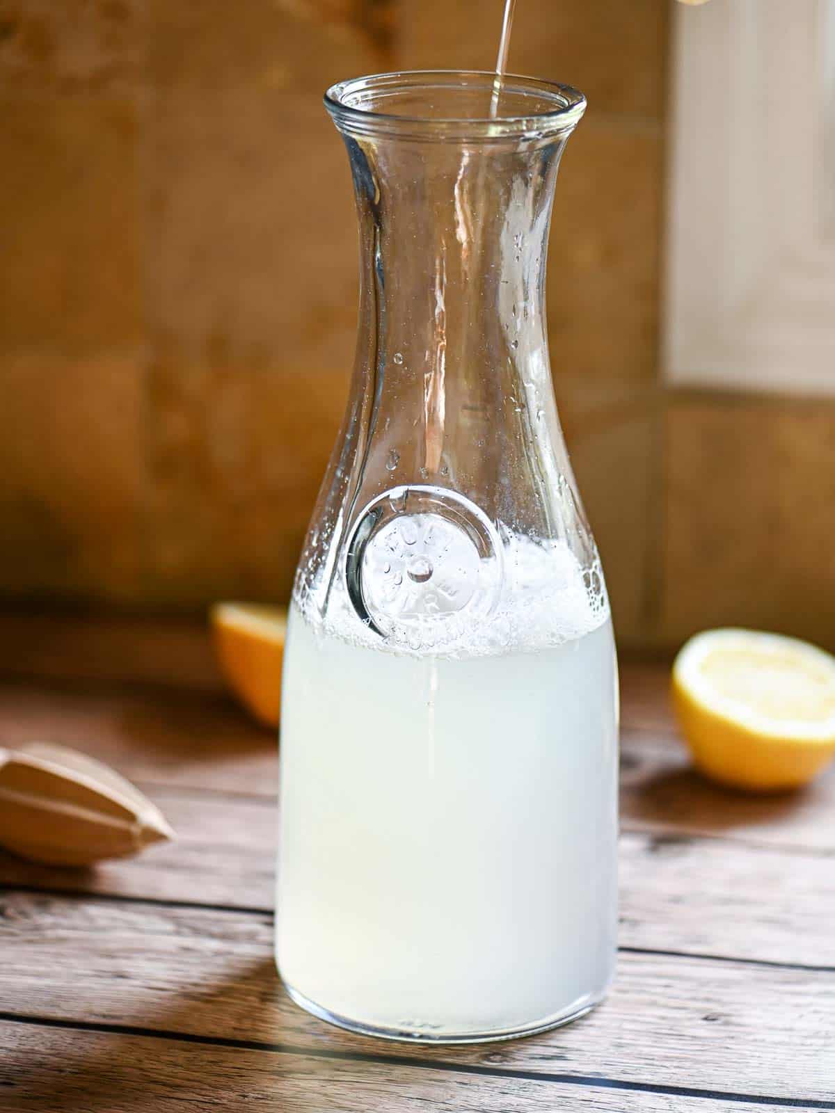 A pitcher filled with lemonade on a wooden table.