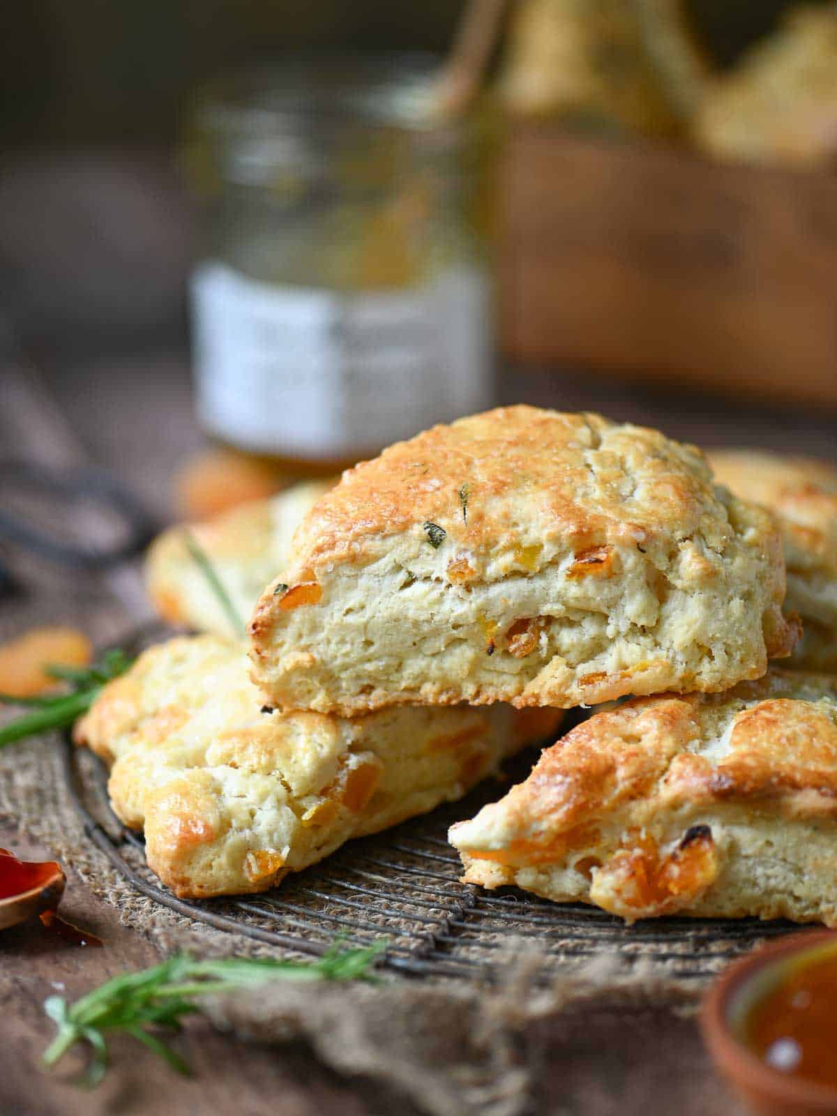 Apricot and rosemary scones on a wire rack on a wood surface.