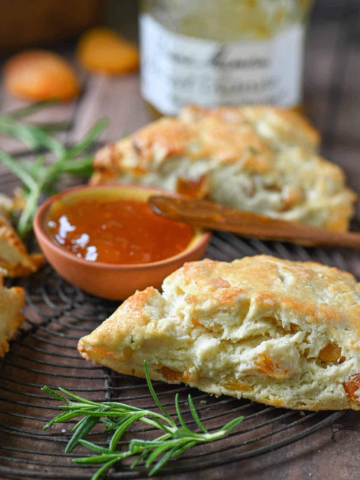 Close-up of scones and jam on a wire rack.
