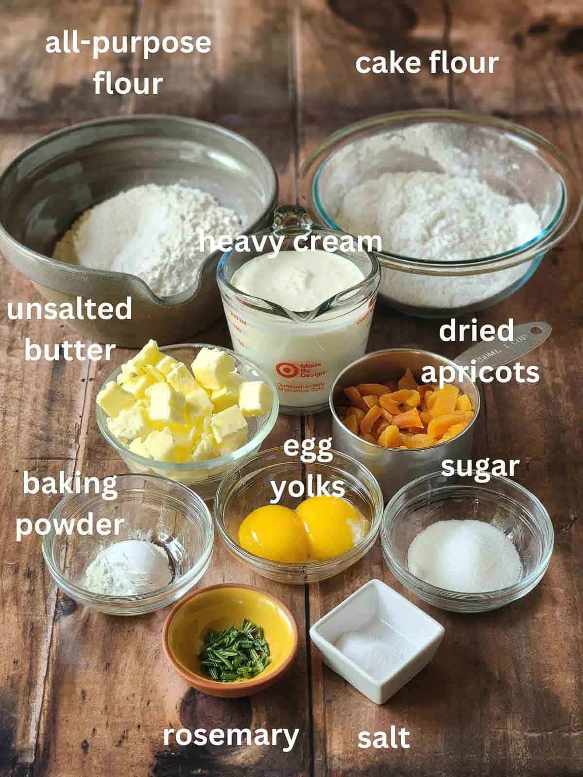 Ingredients for rosemary scones in bowls on a wood surface.