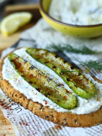 Grilled cucumber toast on a wood board.