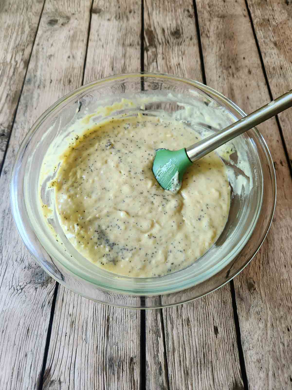 Muffin batter in clear bowl with a spatula.