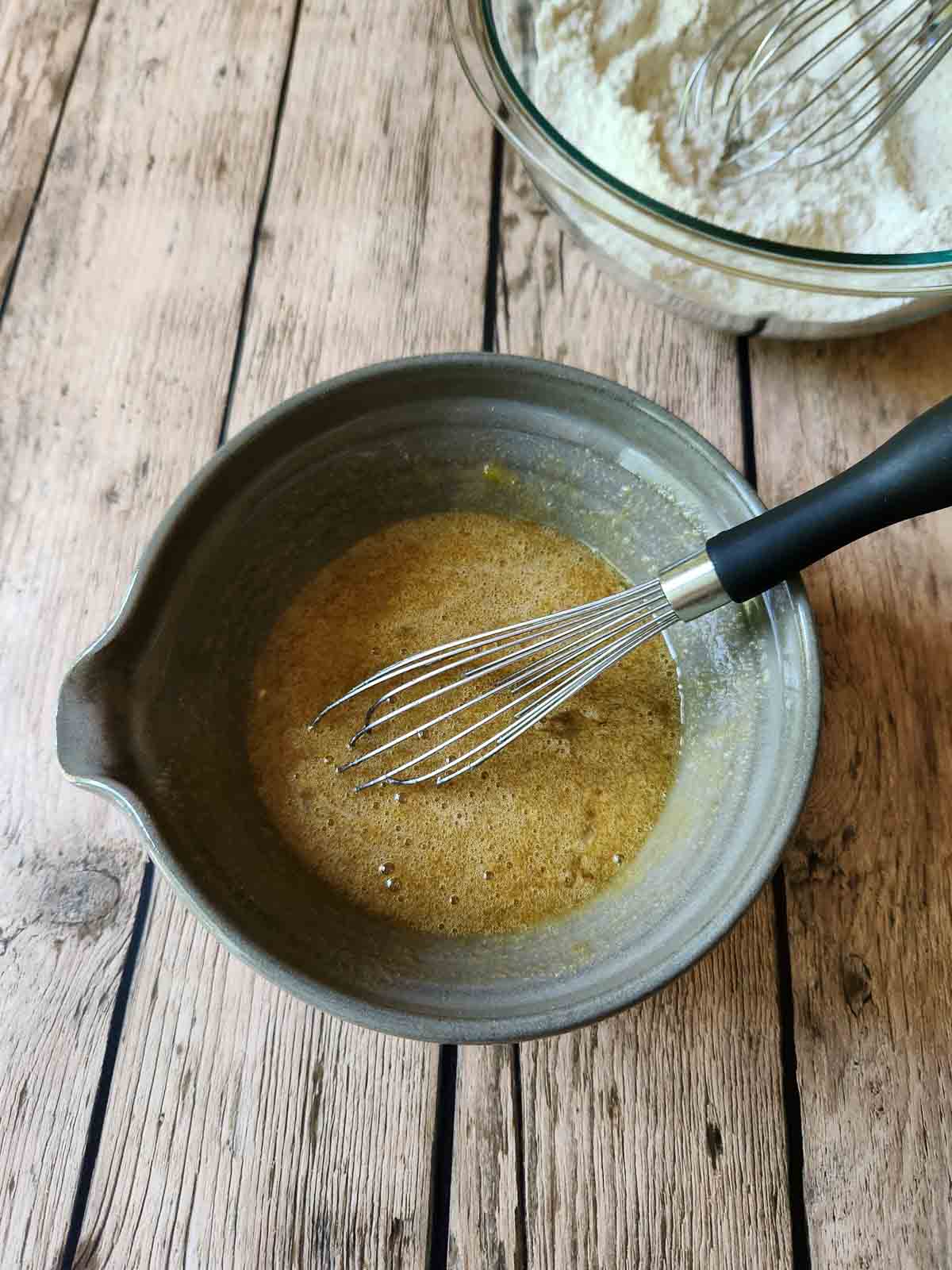 Liquid ingredients mixed in a bowl with a whisk.