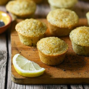 Six mini muffins on wood board with a lemon next to them.
