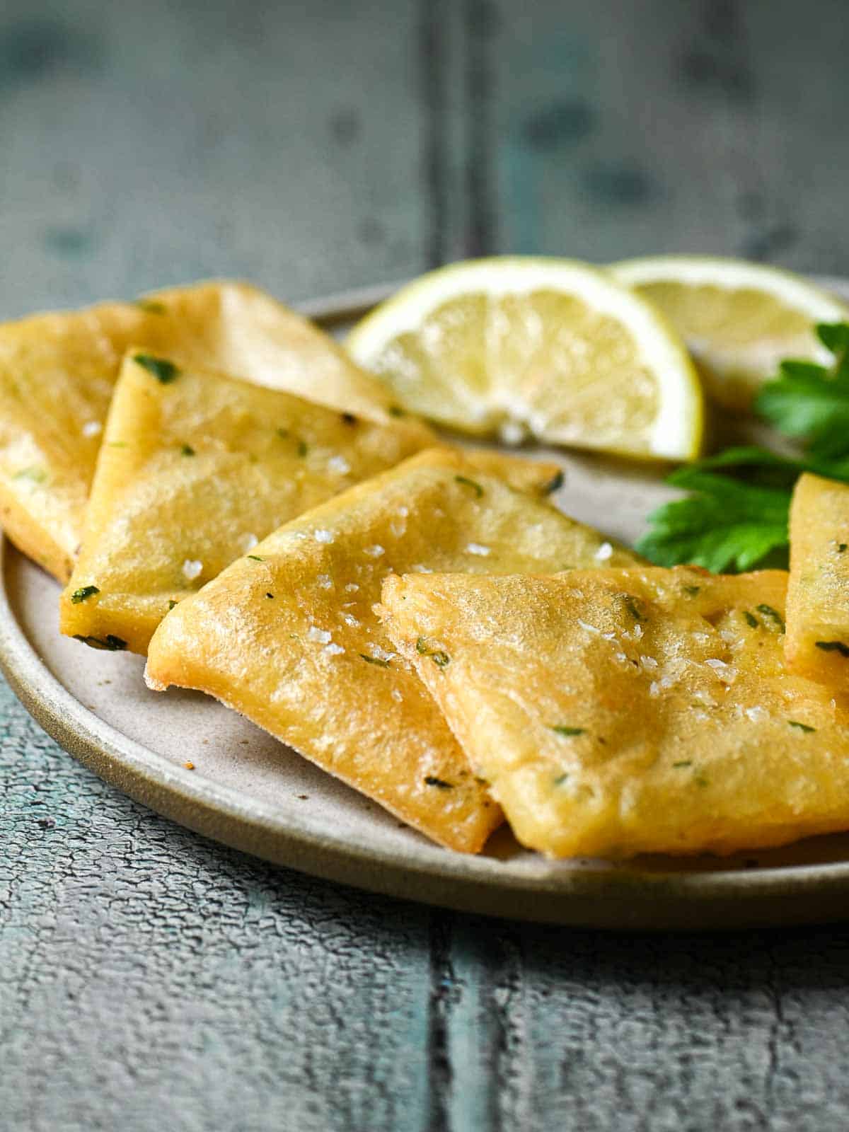 Chickpea fritters in a white plate with lemon wedges.