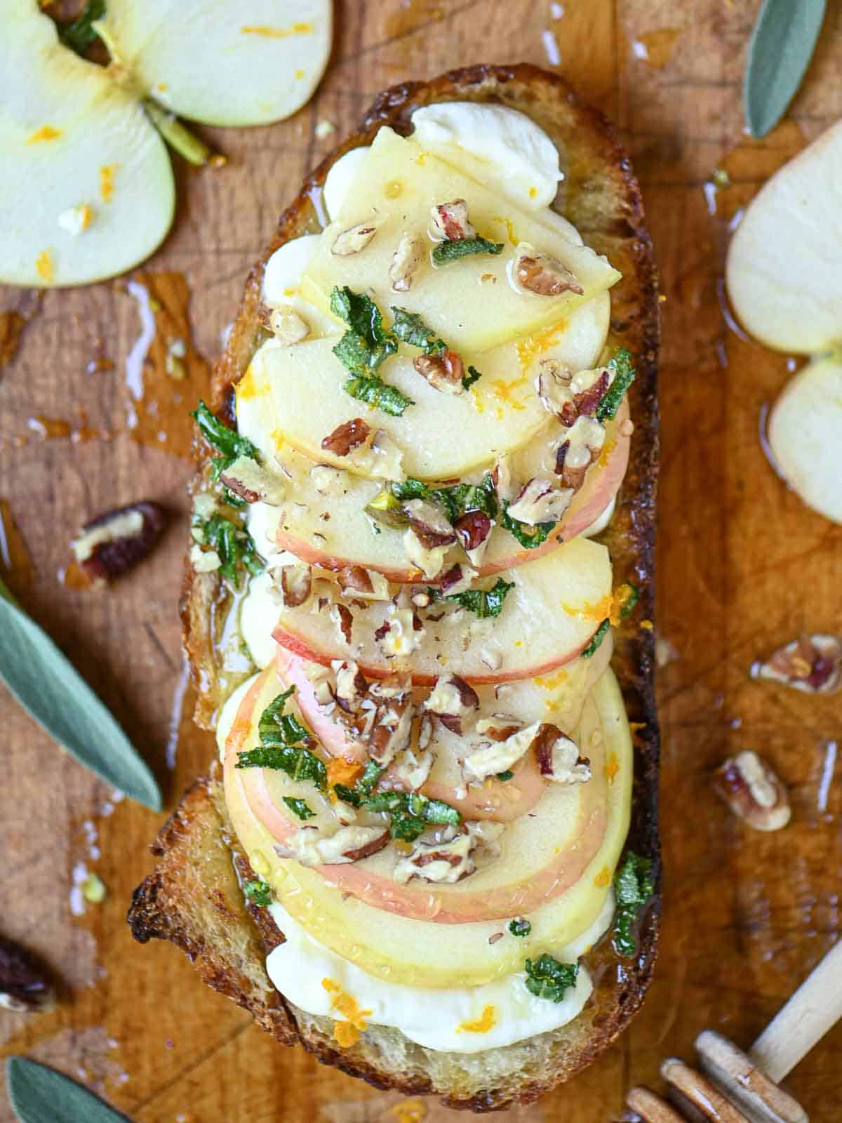 Overhead of apple toast with sage honey on a cutting board.