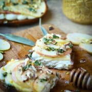 Apple toast sliced open on a cutting board with sage and honey.