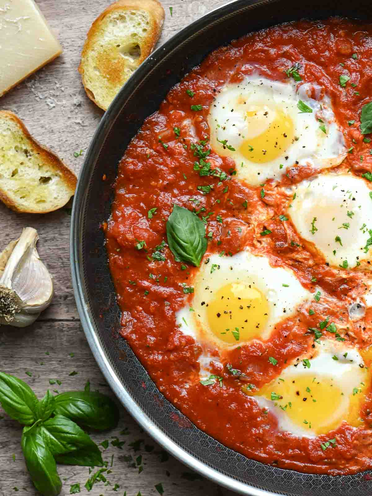 Overview of a skillet of poached eggs in tomato sauce.