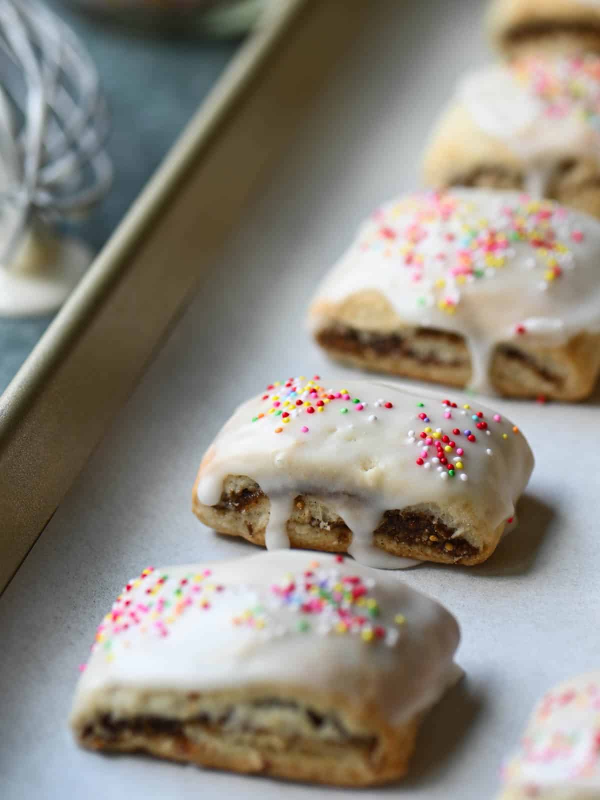 Iced fig cookies on a baking tray with white parchment paper.