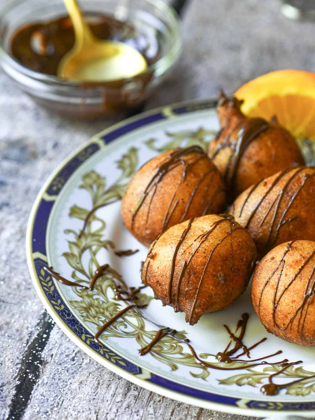 Ricotta donuts with chocolate drizzle on a blue plate.