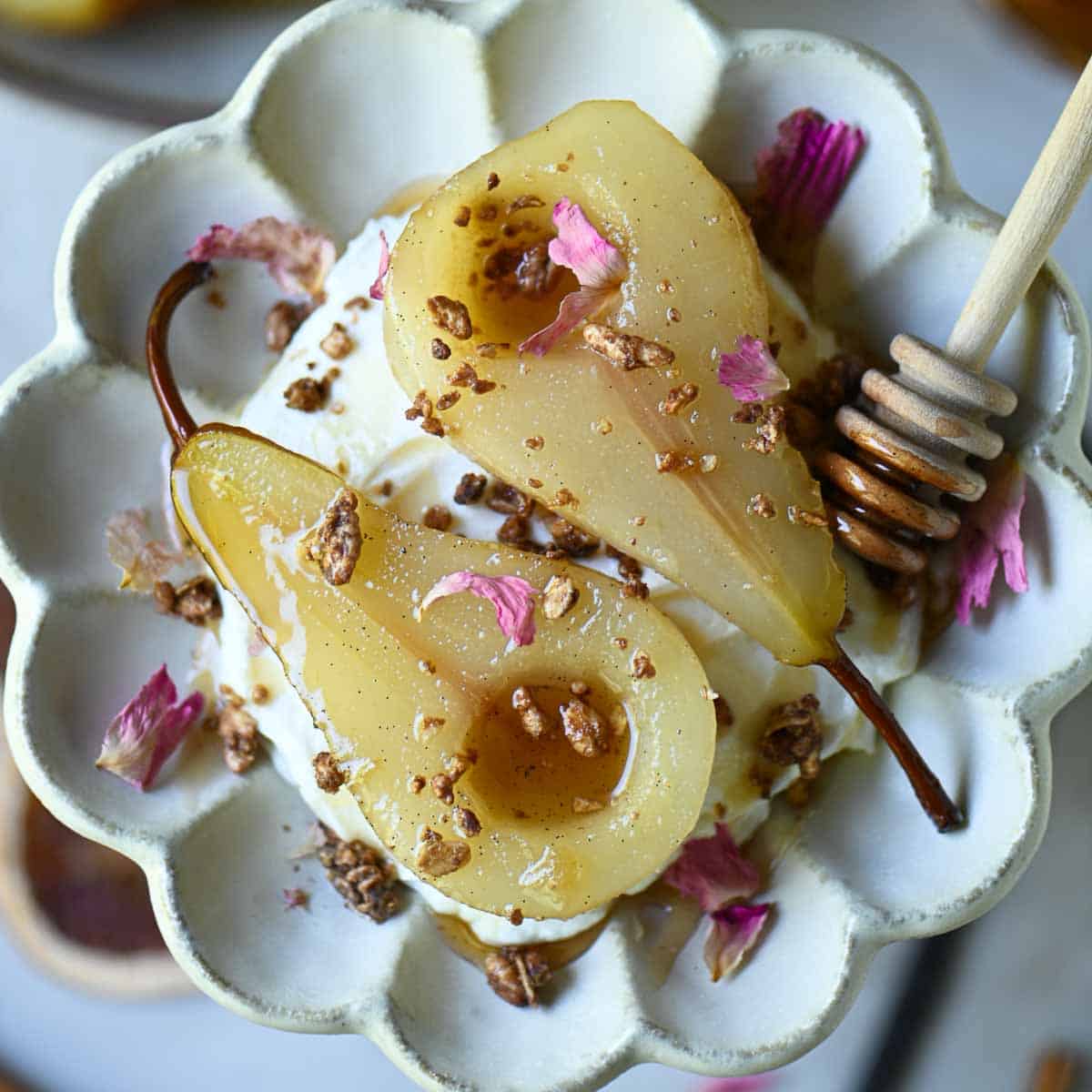 Overhead of poached pears on a flower plate.