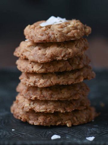 A stack of oatmeal cookies on a metal tray.