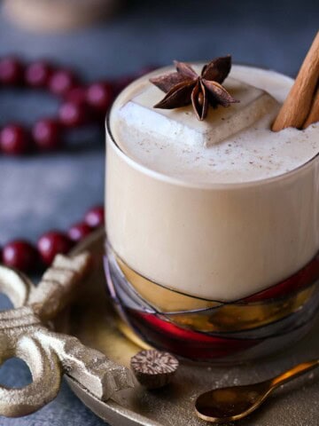 Close-up of a white Russian cocktail with star anise and cinnamon stick on top.
