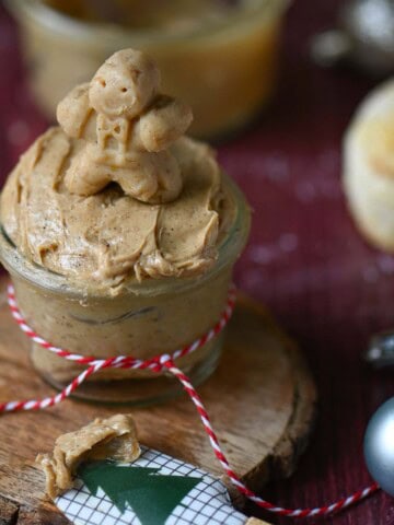 Close- up of a gingerbread man on gingerbread butter in a clear jar.