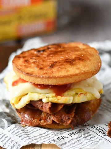 Toaster cake breakfast sandwich with bacon, egg, and cheese on deli paper.