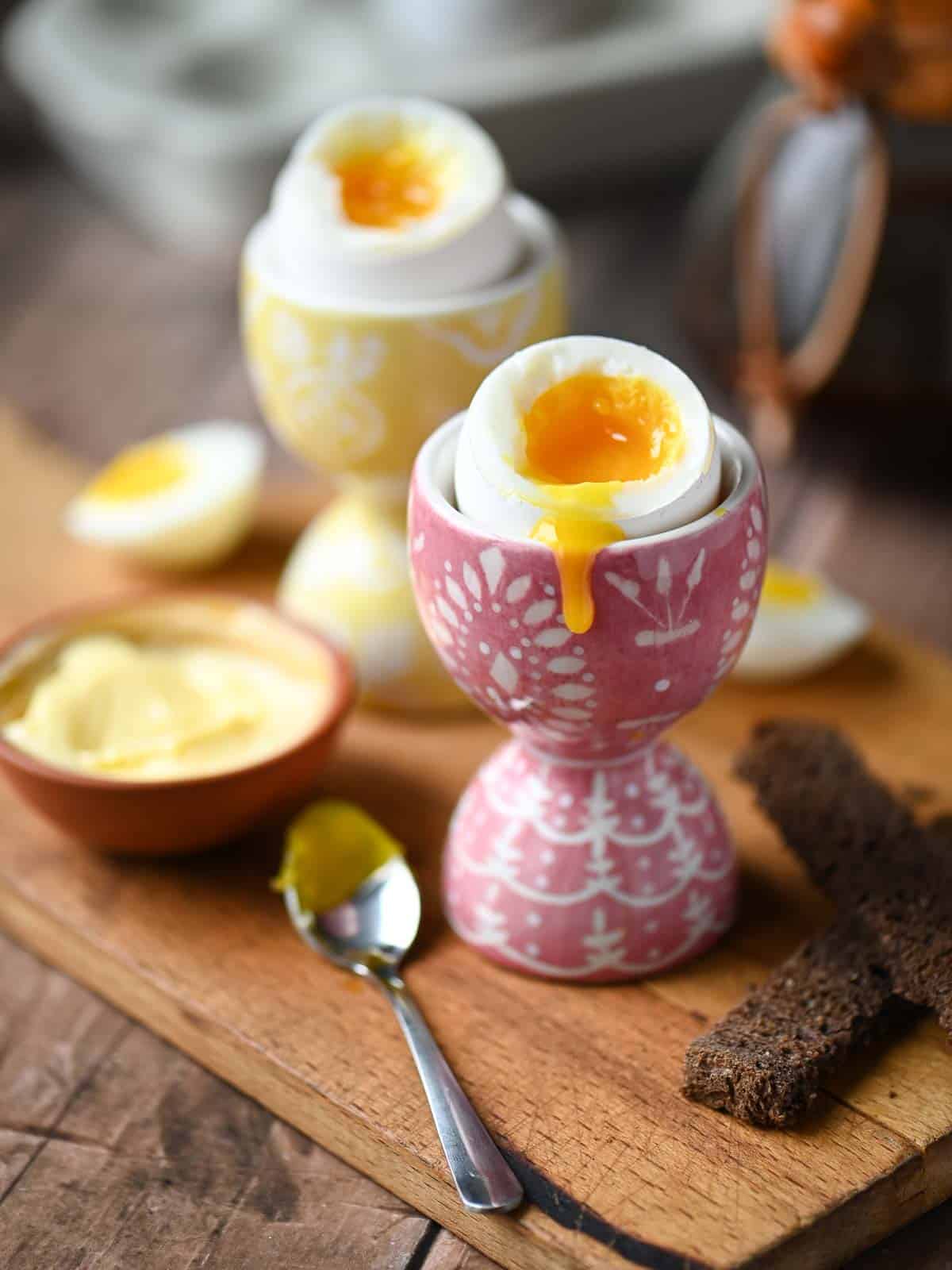 Two soft boiled eggs in egg holders with the yolk dripping down.