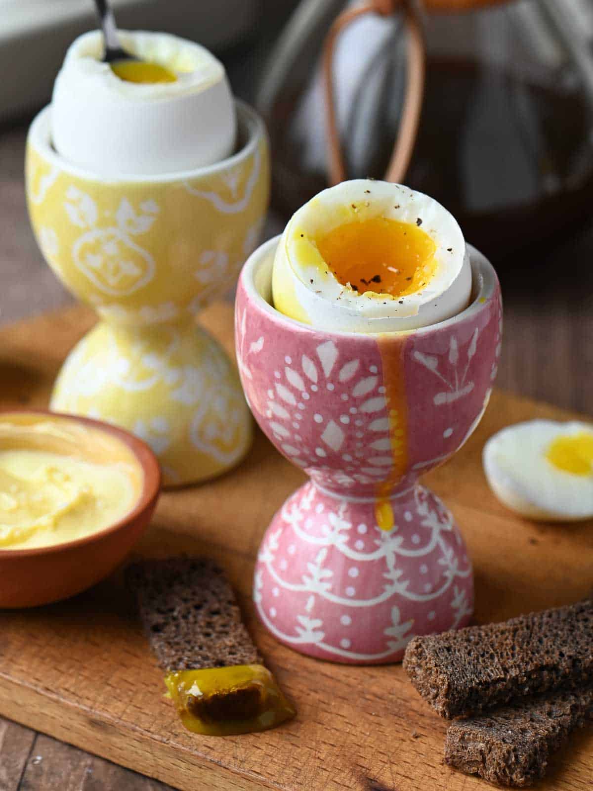 Close up of soft boiled egg in a pink cup on a wooden board.
