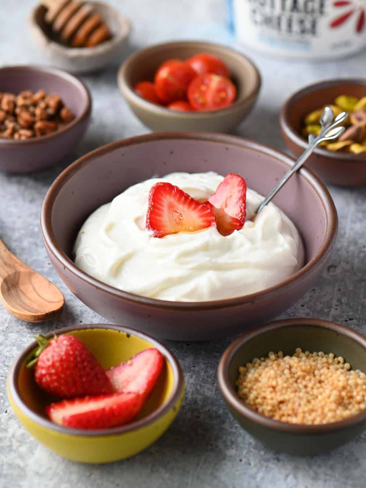 Cottage cheese bowl surrounded by smaller bowls with toppings.