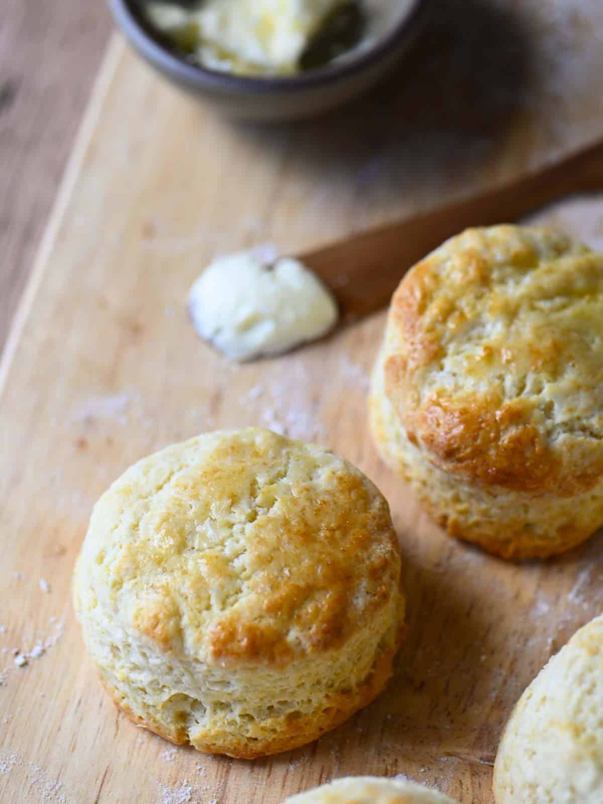 Angled view of biscuits on a cutting board with butter.