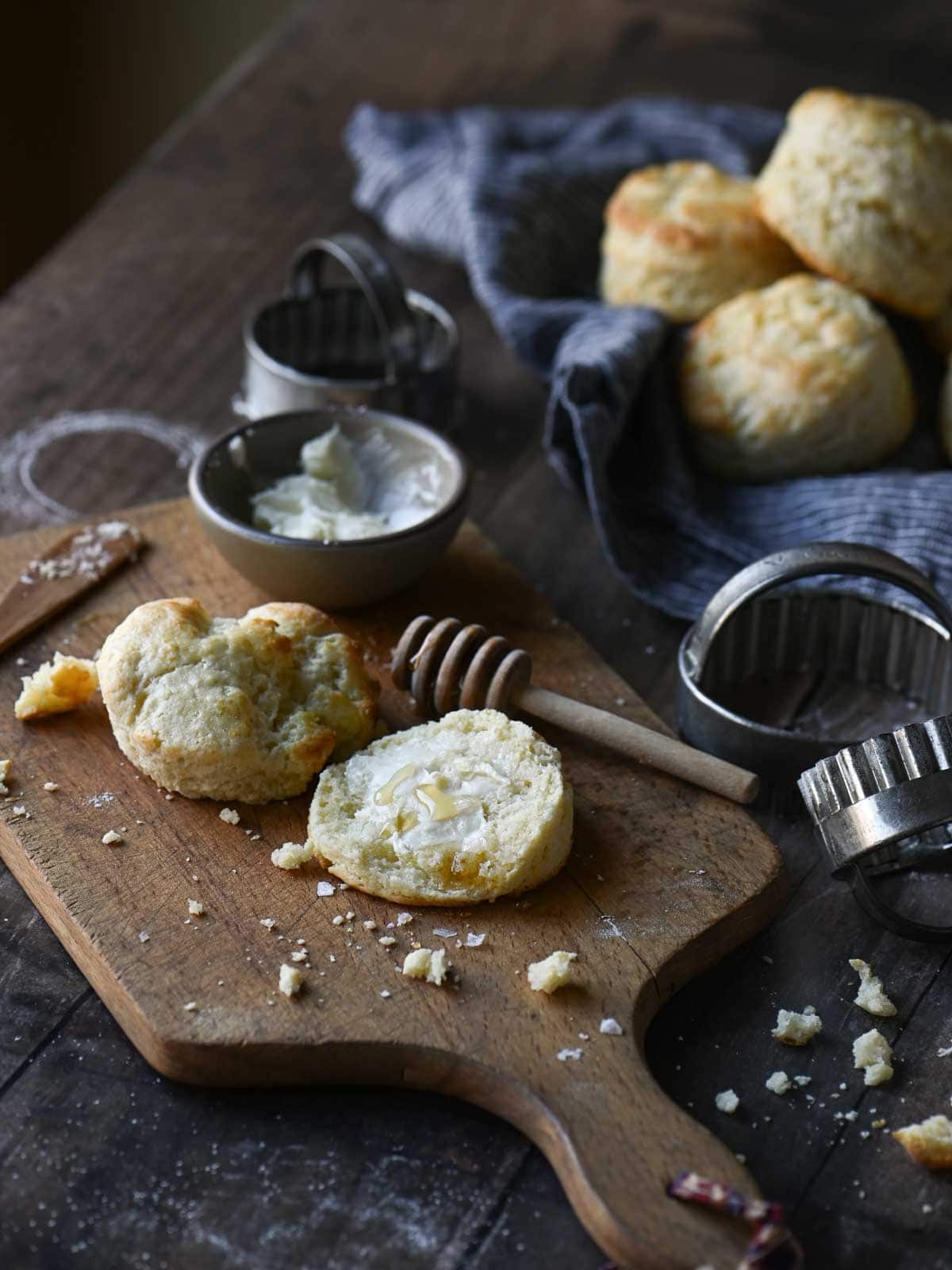 Angled view of a table breakfast scene with biscuits, butter and crumbs scattered around it.
