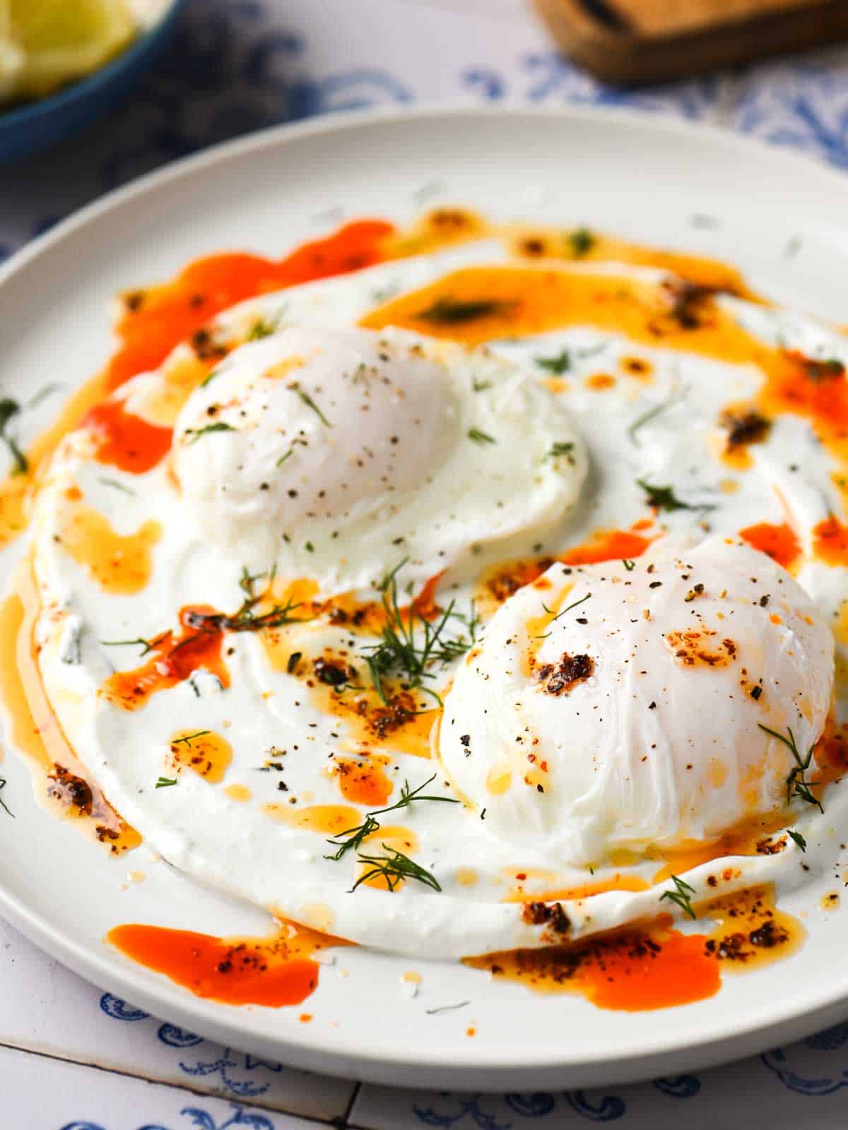 Close-up of chili-poached eggs on a white dish.