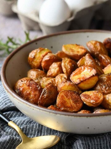 Bowl of roasted potatoes on a blue striped napkin.