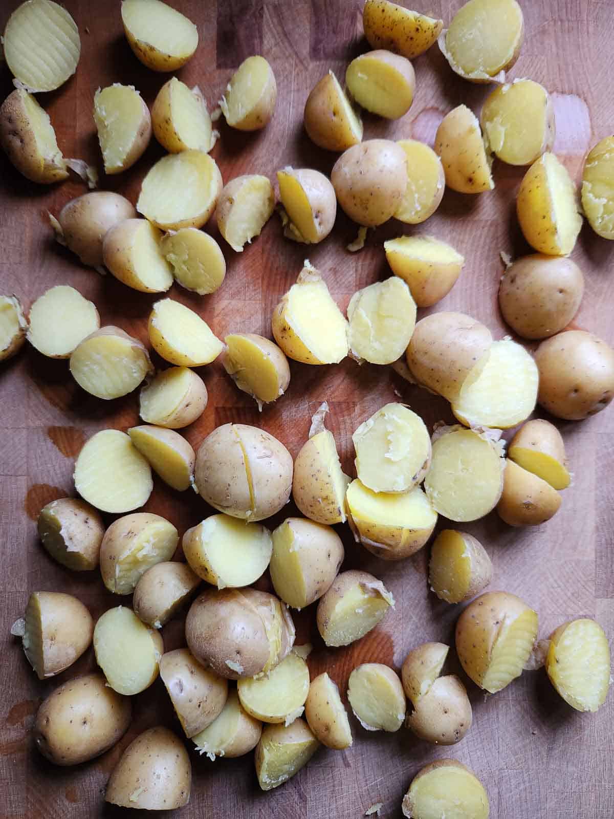 Cooked potatoes cur in half in a cutting board.
