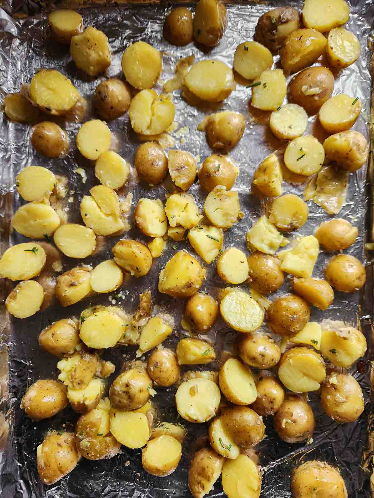 Oiled potatoes on a baking sheet ready for the oven.