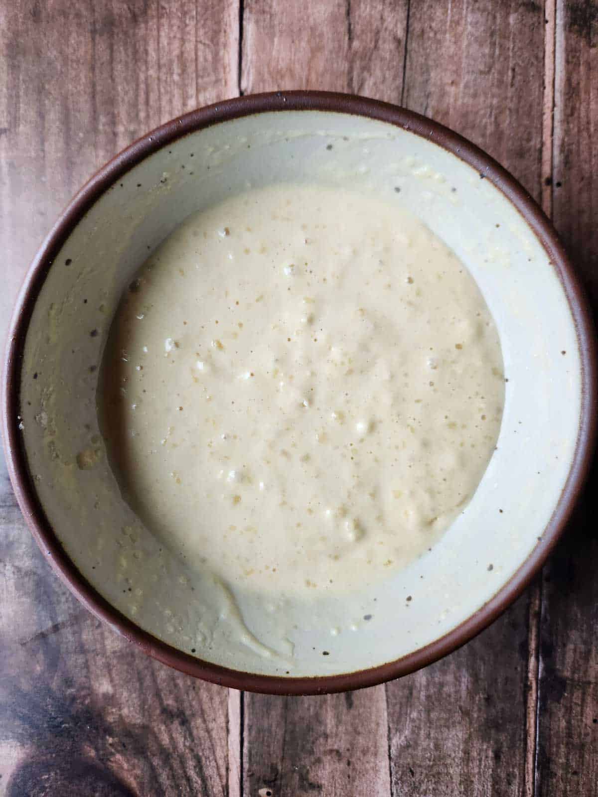 Mixed waffle batter in a beige bowl.