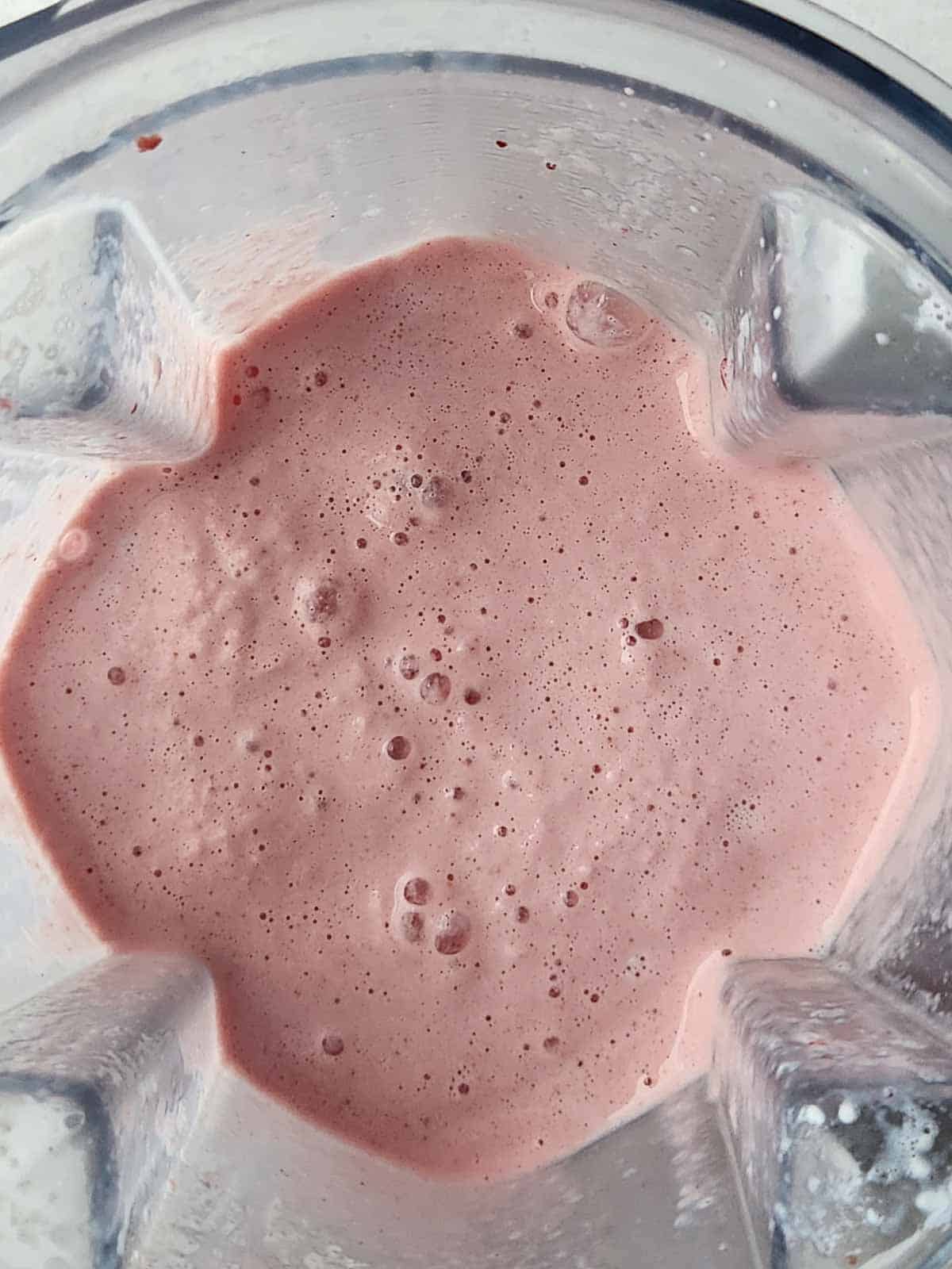 Overhead of a blended pink smoothie in a blender.