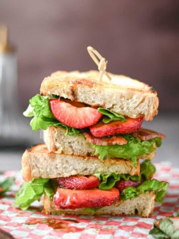 Eye level view of a stacked BLT view with Strawberries.