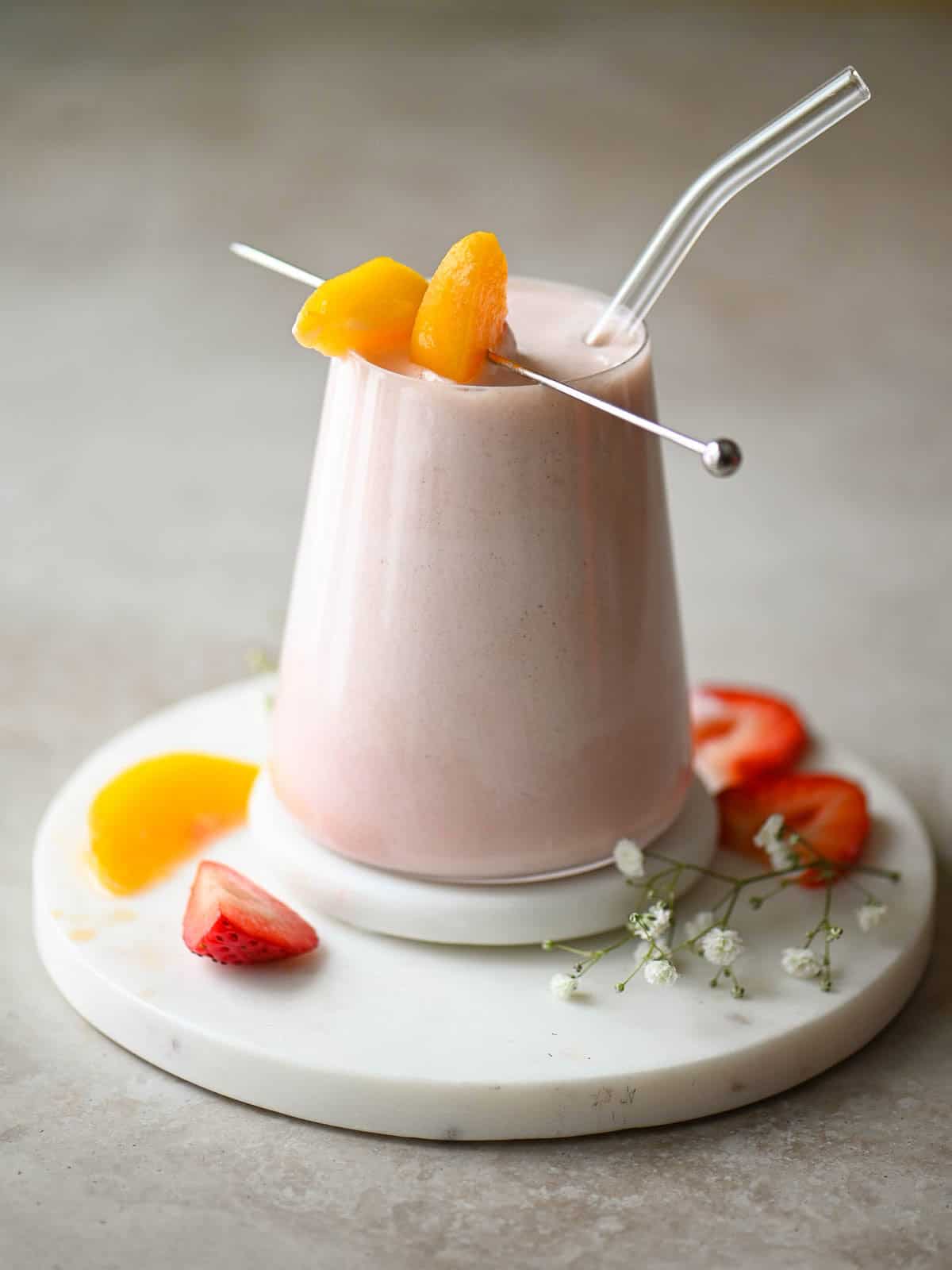 An eye level view of a smoothie in a clear glass with a clear straw.