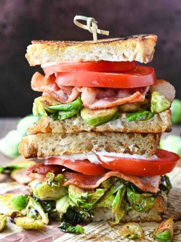 Stacked brussel sprout BLT sandwiches on a wooden board.