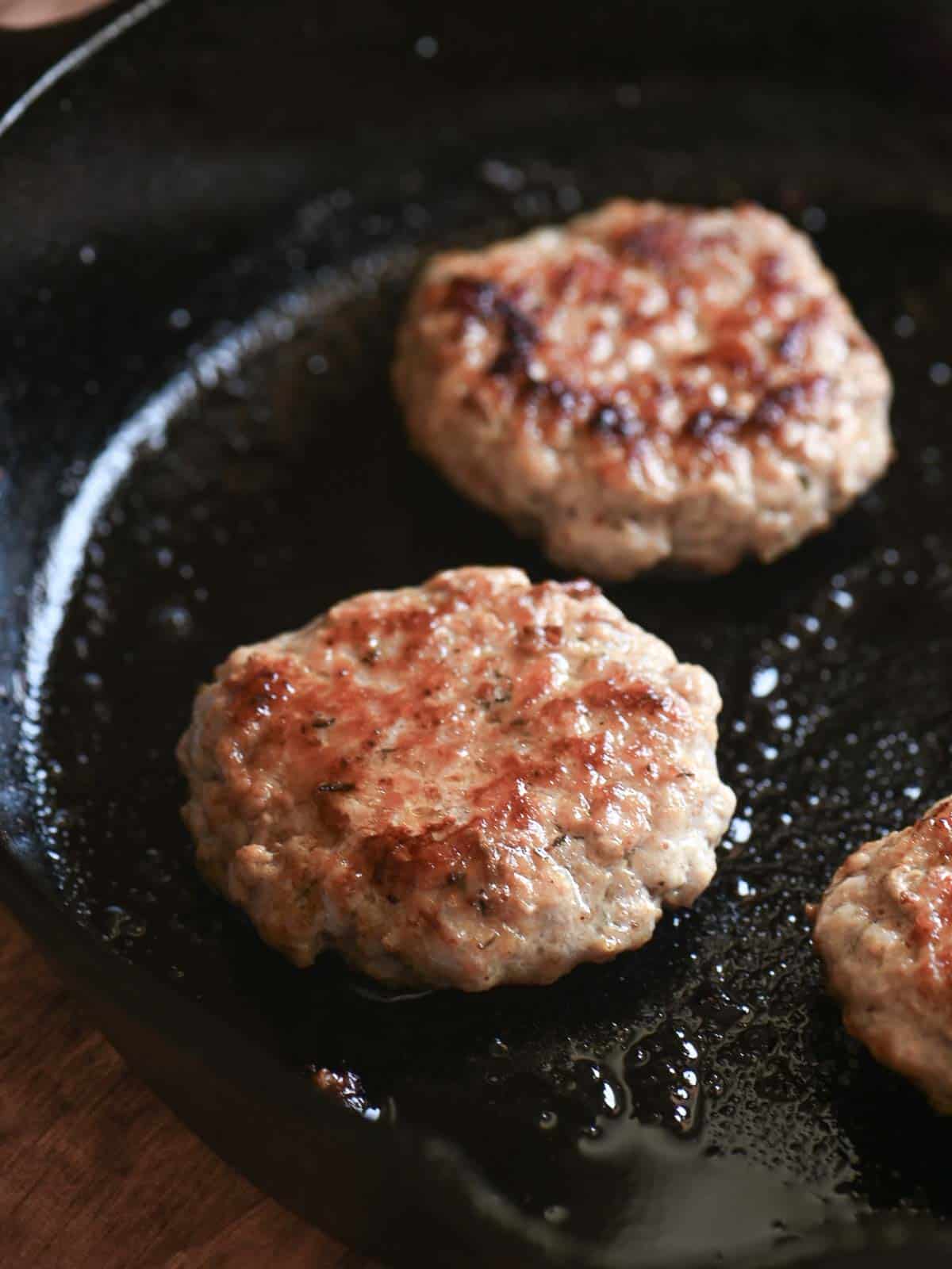 Breakfast sausage patties in a cast iron skillet.