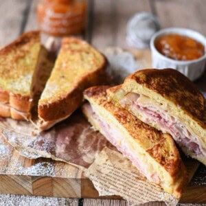Sliced Monte Cristo sandwiches on a wooden board with apricot jam.