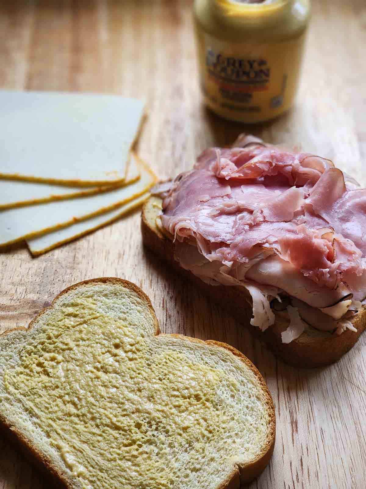 Prepared meat and cheese on a deli board to make a sandwich.