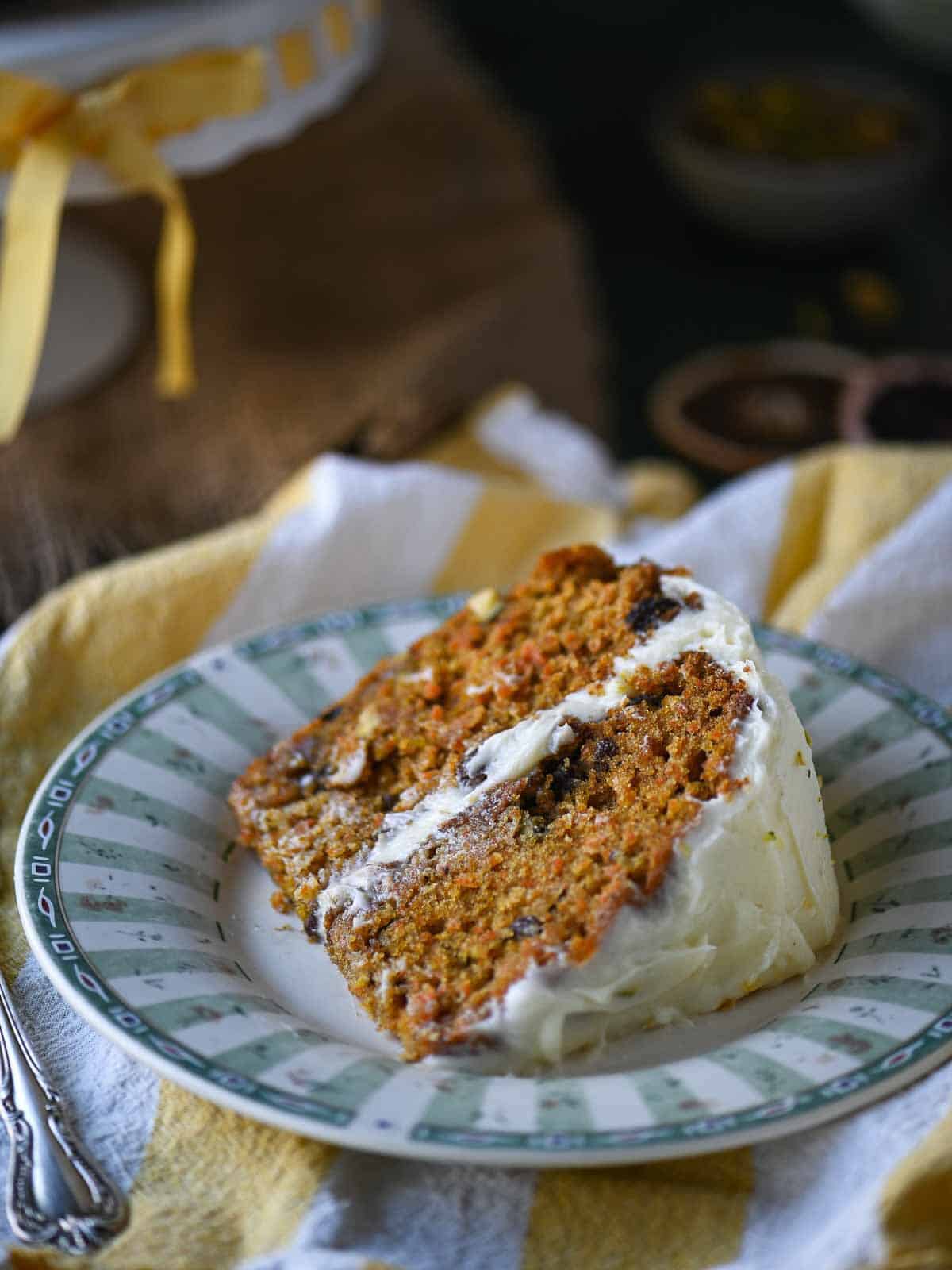A slice of carrot cake showing the two layers on a green and white plate.