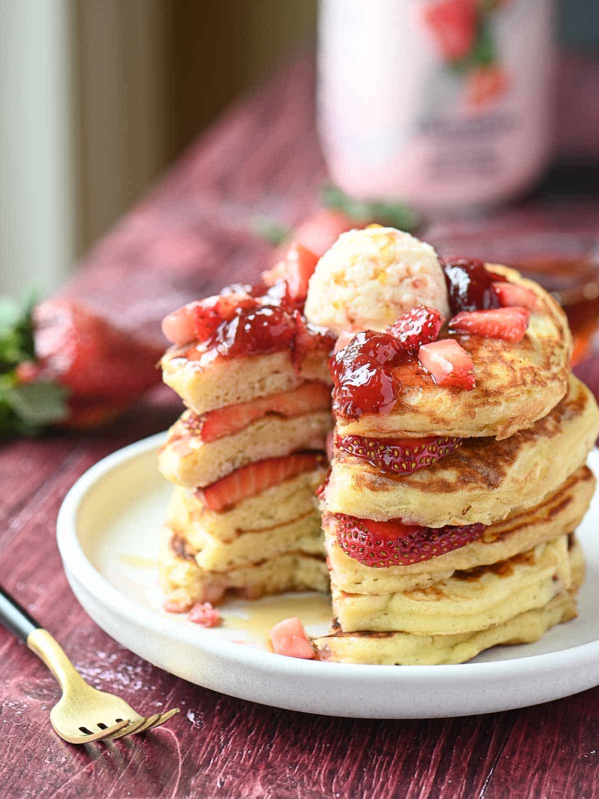 Strawberry kefir pancake stack cut open showing the inside on a white plate.