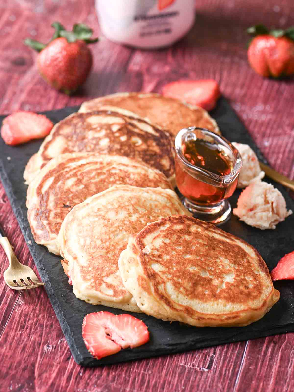 A spread of strawberry pancakes on a black platter.